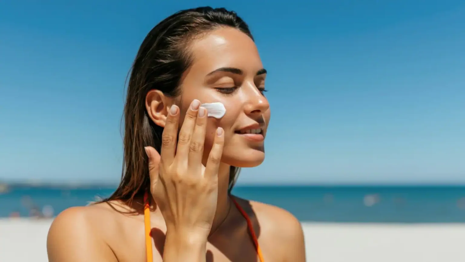 women applying sunscreen on beach which is causing wite cast to her skin.